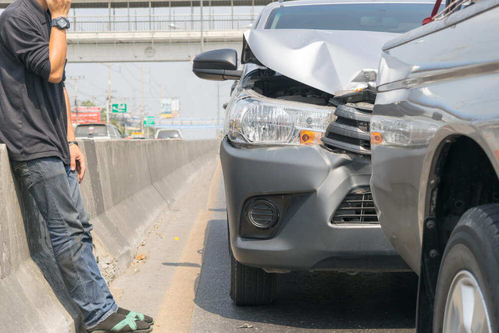 Zwei Autos nach einem leichten Unfall auf der Straße, eine Person telefoniert in der Nähe und organisiert vermutlich ein Schadengutachten